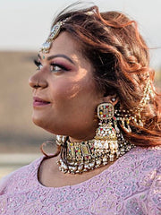 Women with intricate gold-toned jewelry including a detailed necklace, maang tikka, and earrings.