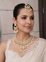Woman wearing traditional Indian jewelry including a necklace, earrings, and a headpiece.