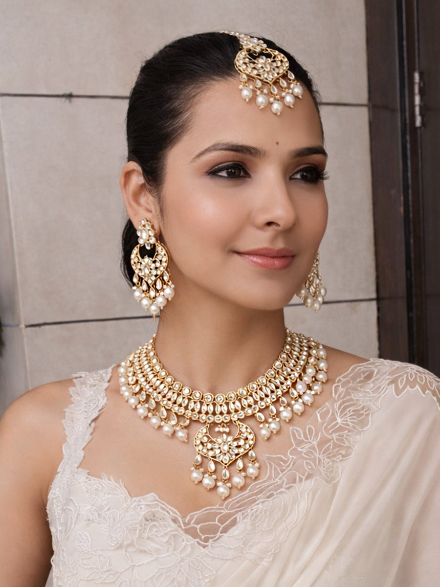 Woman wearing traditional Indian jewelry including a necklace, earrings, and a headpiece.