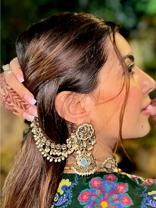 Women wearing detailed gold earring and green outfit with floral patterns.