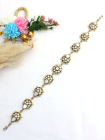 Golden Sheeshphool with intricate circular designs on a white surface, surrounded by dried and fresh flowers.