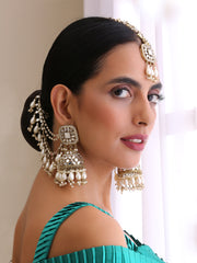 Women wearing intricate pearl and gold jewelry with a teal dress. 
