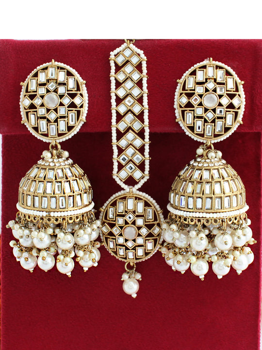 Intricate gold earrings with white gemstones, displayed on a red velvet background.