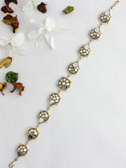 Golden Sheeshphool with intricate circular designs on a white surface, surrounded by dried and fresh flowers.
